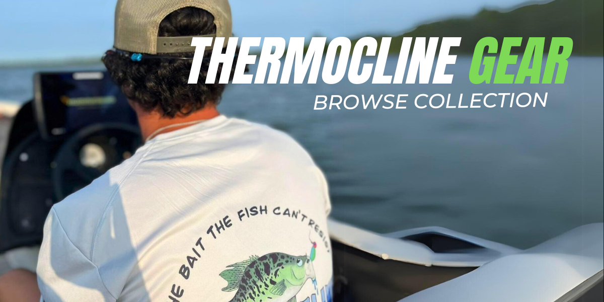 A person seated on a boat wearing a white Thermocline Lures t-shirt with a colorful fishing lure design and the tagline, 'The bait the fish can't resist.